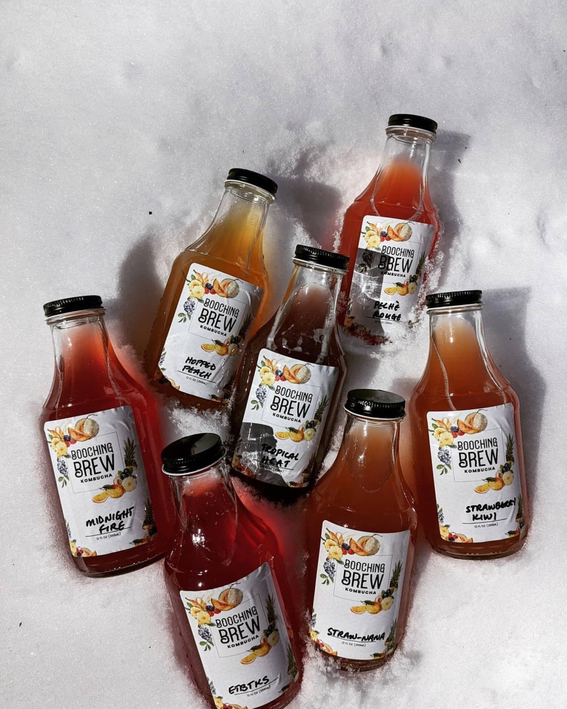 Seven bottles of kombucha in a snow bank.