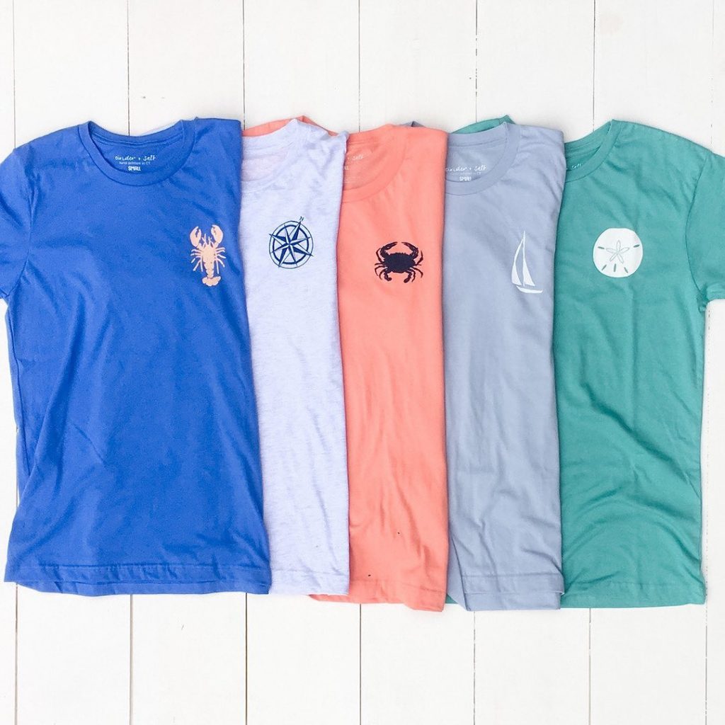 A variety of t shirts with nautical icons on the upper left side.