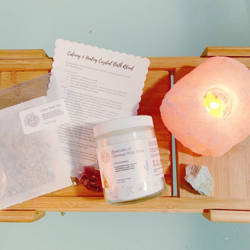 A wooden tray with a salt lamp and jar of skincare product and accompanying paper materials.