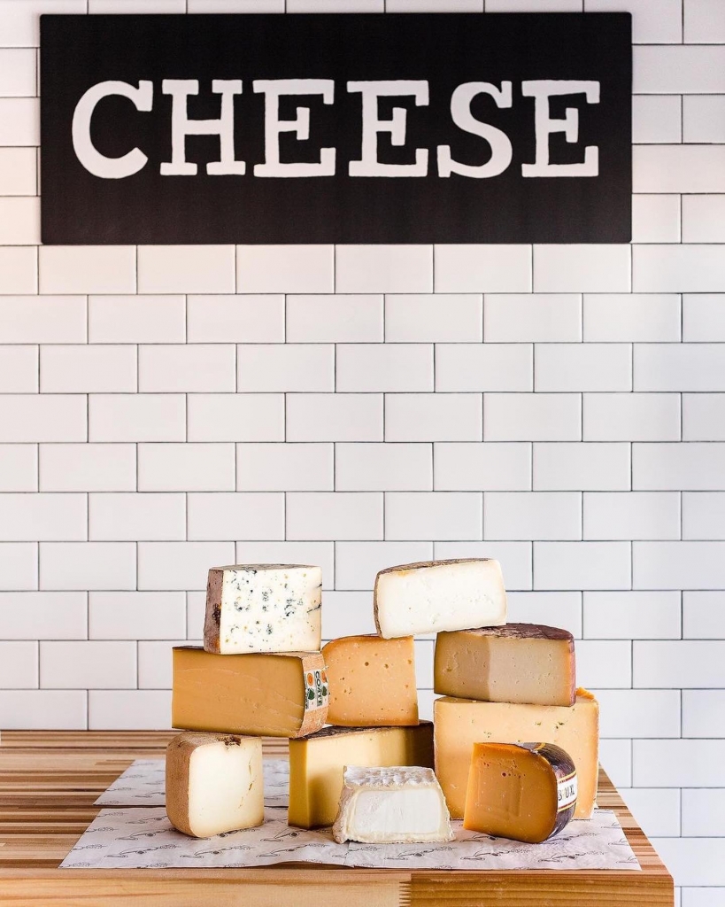 Various blocks of cheese in front of a sign saying "cheese"