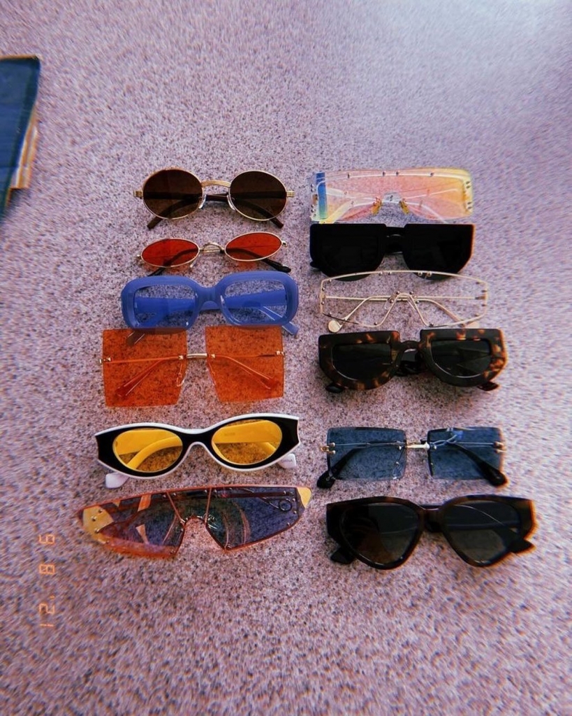 Twelve pairs of trendy sunglasses with smaller frames in a variety of colors.