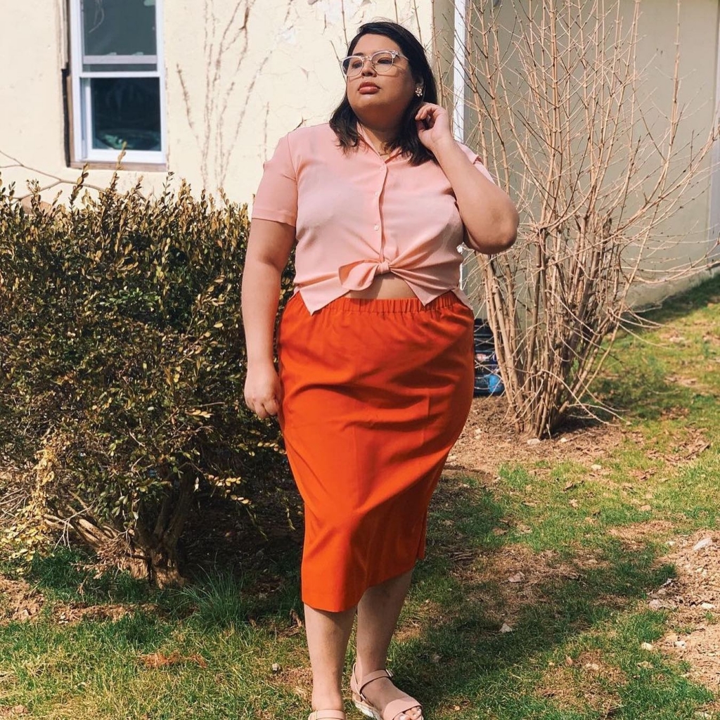 Woman wearing a thrifted orange skirt and pink button down shortsleeve top.