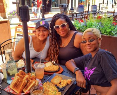 Three black women enjoying breakfast at Sunberry's outdoor on Pratt Street.
