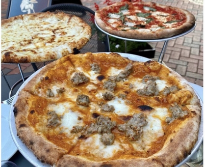Three pizzas with varying toppings on an outdoor table on Pratt Street