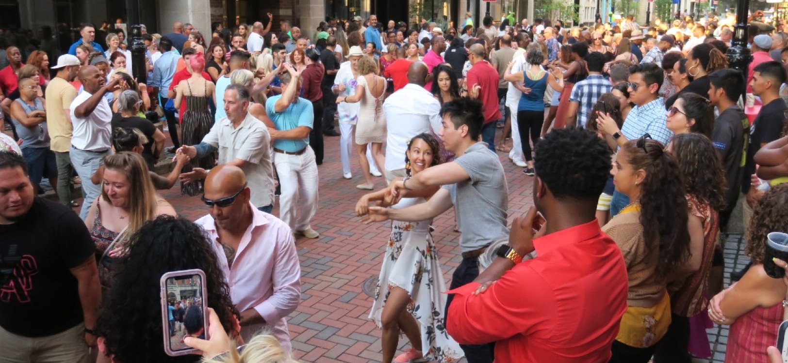 A crowd of people dance on the Pratt Street Patio at Salsa Socials Night